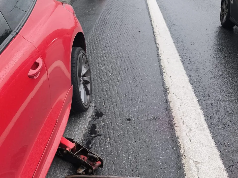 Yol kenarında emniyet konisiyle korunan alanda kriko ile lastik değişimi — TEM / O-4 için örnek çalışma fotoğrafı